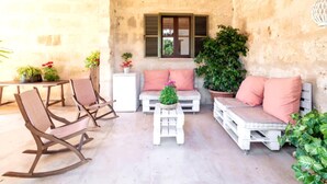 Un patio acogedor con muebles rústicos, una mesa blanca y plantas en macetas.