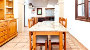 Una cocina con encimera de mármol, armarios de madera y un comedor con sillas.
