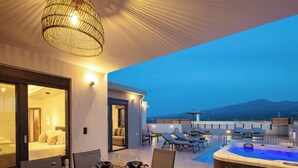 A modern outdoor dining area with a hot tub, lounge chairs, and a view of the mountains. - Villa Vacasa - A Heaven of Luxury in the Heart of Crete (Aggeliana)