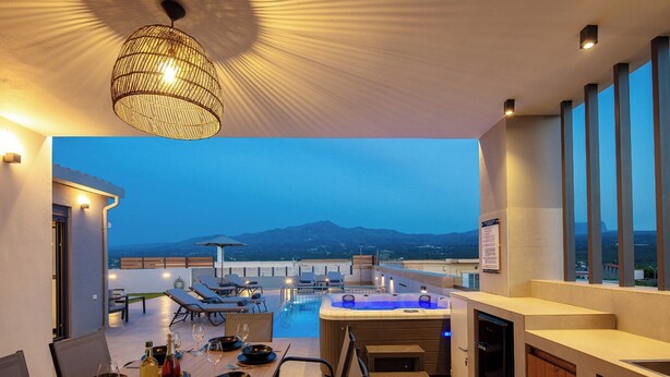 A rooftop terrace with a hot tub, dining area, and a view of the mountains. - Villa Vacasa - A Heaven of Luxury in the Heart of Crete (Aggeliana)