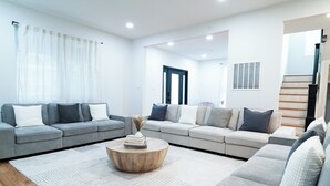 A modern living room with a grey sofa set, a wooden coffee table, and a white rug. - Spacious 7-bedroom,  5 Full bathroom house. Walkers Paradise No car required! (Arlington)