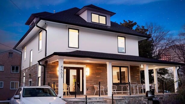 A modern two-story house with a covered patio, a car parked in front, and a stone wall. - Spacious 7-bedroom,  5 Full bathroom house. Walkers Paradise No car required! (Arlington)