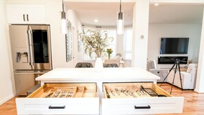 A modern kitchen with a central island, white cabinetry, and a stainless steel refrigerator. - Spacious 7-bedroom,  5 Full bathroom house. Walkers Paradise No car required! (Arlington)