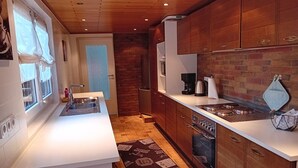 Eine moderne Küche mit Holzschränken, einer weißen Arbeitsplatte und einem eingebauten Backofen.