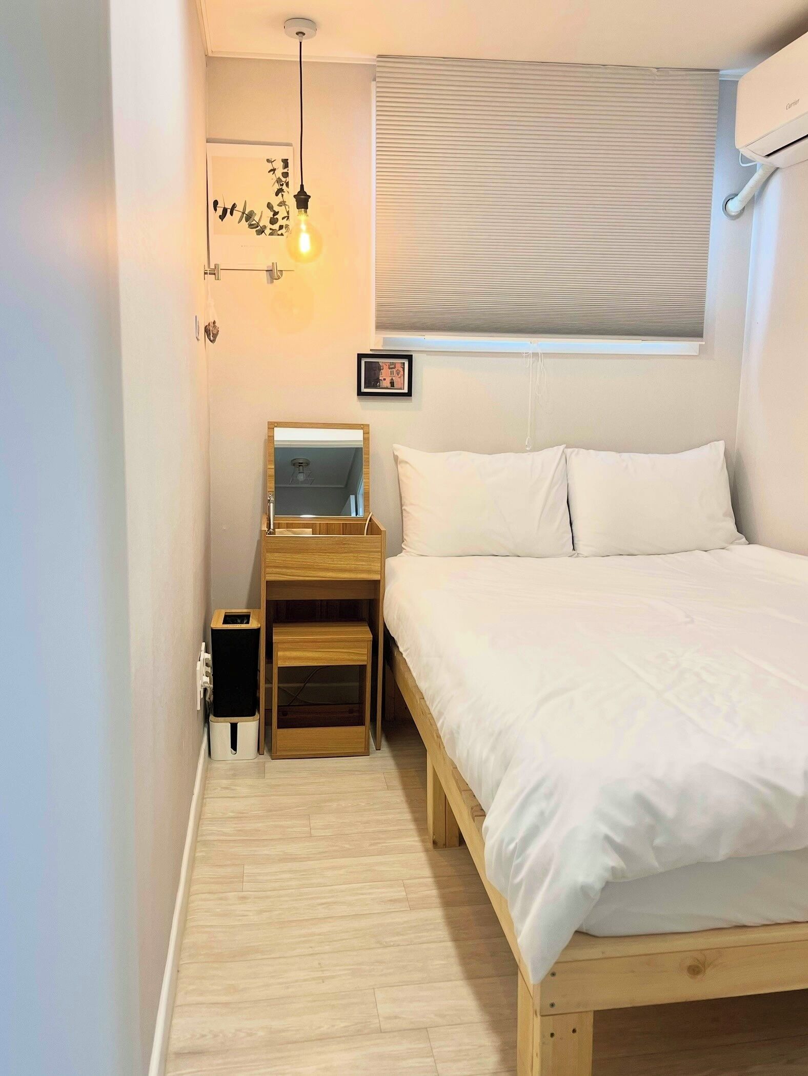 A bedroom with a wooden bed, a nightstand with a mirror, a small wooden cabinet, and a ceiling light fixture.