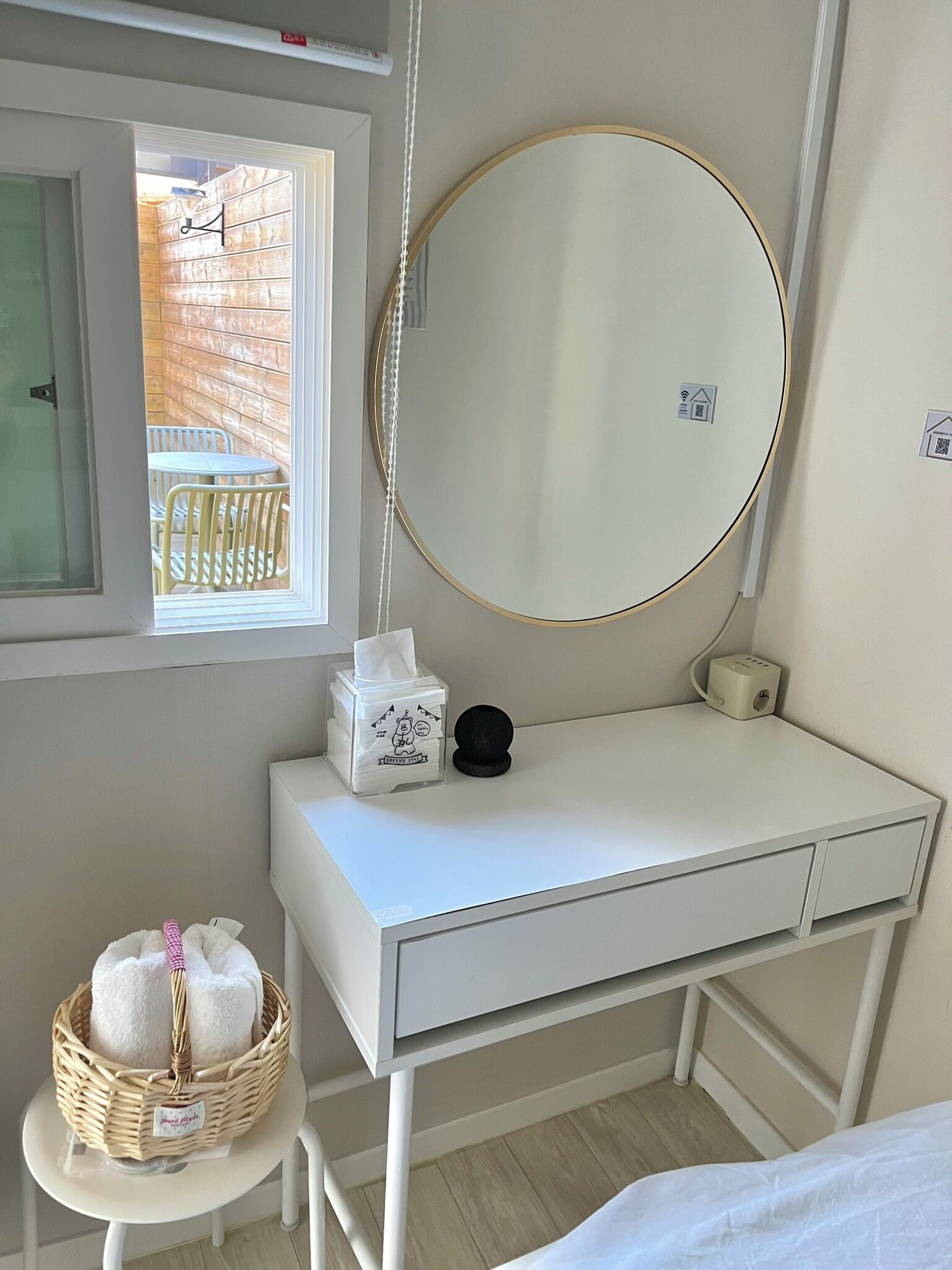 A white vanity with a round mirror, a tissue box, and a black object on the counter.