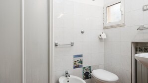 Un baño con inodoro, bidé y una ventana pequeña.