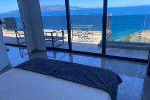 A bedroom with a large window overlooking a coastal view.