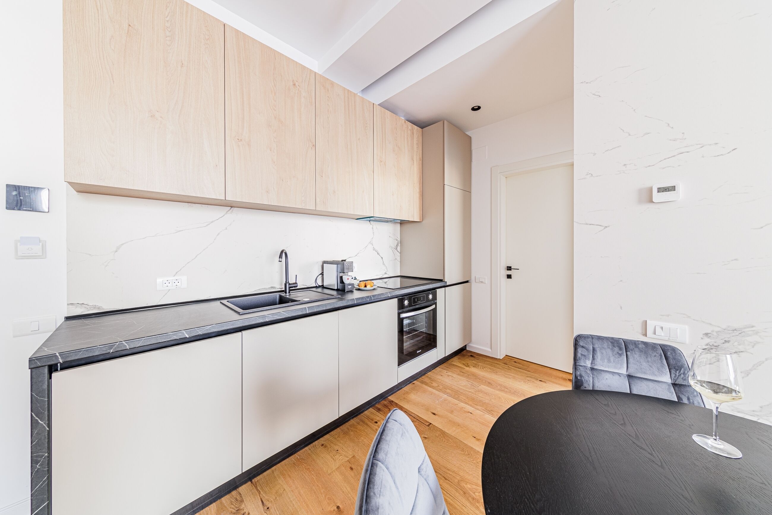A modern kitchen with wooden cabinets, a black countertop, and a built-in oven.