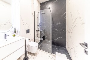 A modern bathroom with a glass-enclosed shower, a white sink, and a toilet. - CAVAR APARTHOTEL (Bucharest)