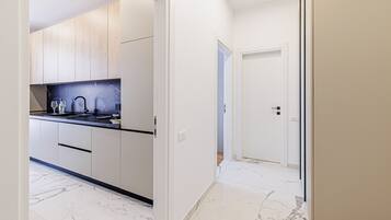 A modern kitchen with white cabinets, a black countertop, and a marble backsplash.