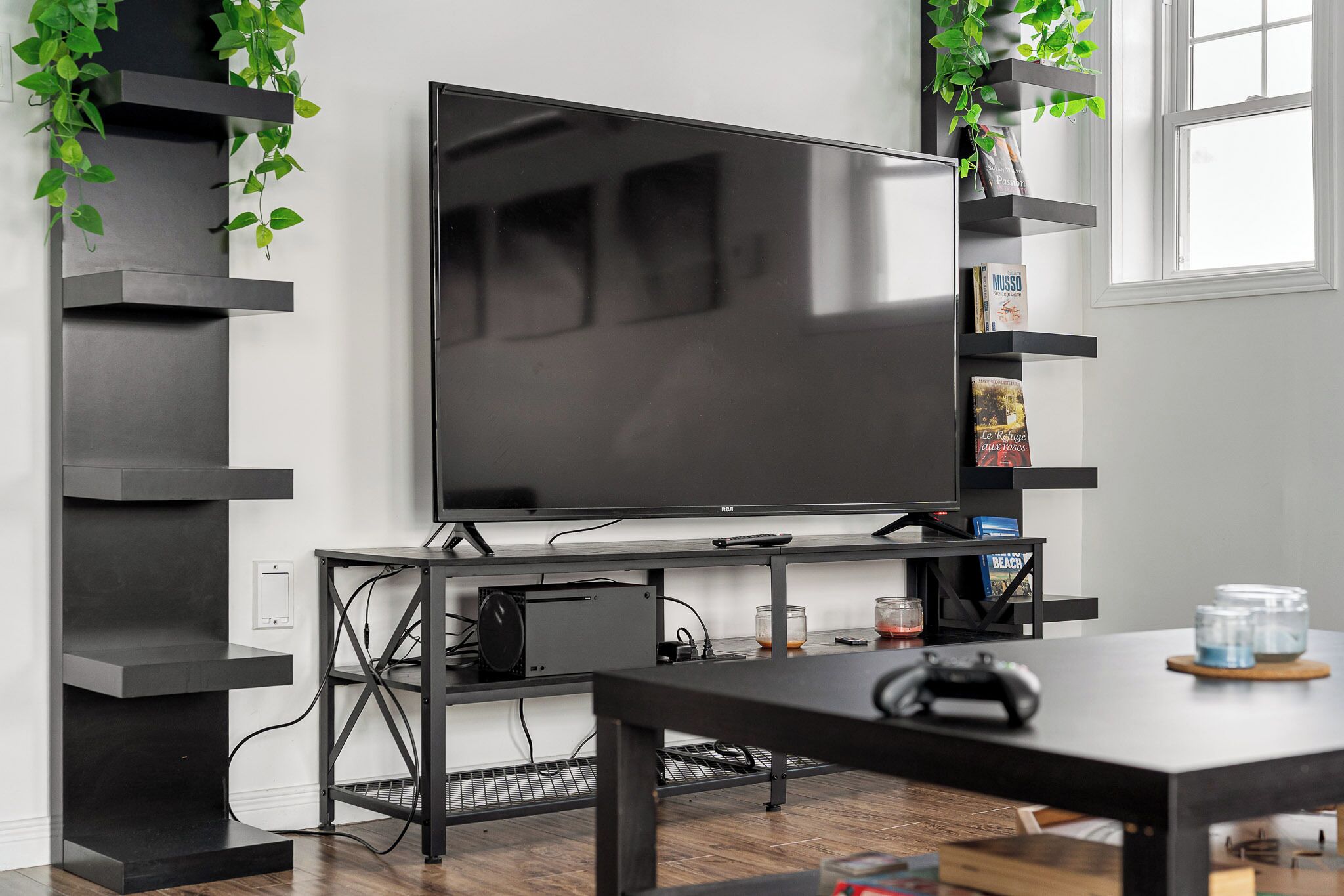 Uma sala de estar moderna com uma televisão de tela plana grande, um console de jogos e uma mesa de centro.