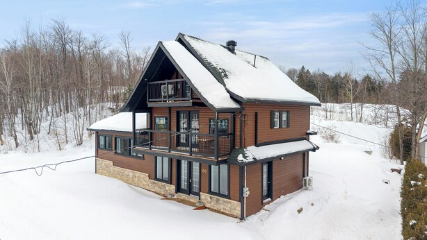 A two-story wooden cabin with a balcony, surrounded by snow-covered trees. - Escape to Grandes-Piles (Grandes-Piles)