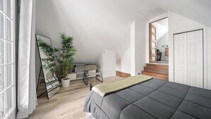 A bedroom with a bed, a mirror, a potted plant, and a staircase leading to another room. - Escape to Grandes-Piles (Grandes-Piles)
