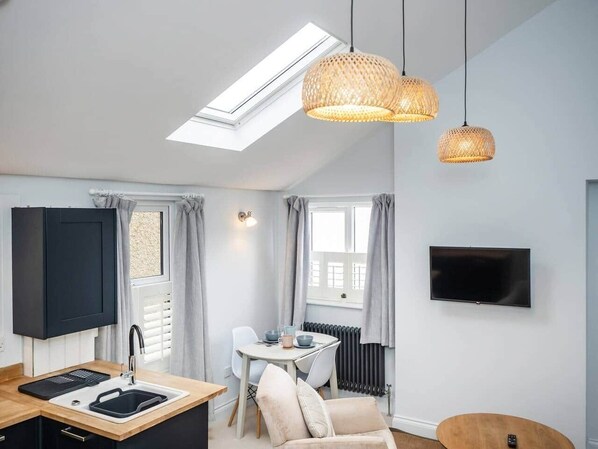 A compact living space with a kitchen, dining area, and a TV mounted on the wall.