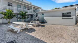 Un edificio su due piani con una zona esterna coperta, una scala e un tavolo da picnic.