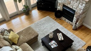 A living room with a sectional sofa, a coffee table, a fireplace, and a television. - Beautiful Kent Island Getaway with Pool (Stevensville)