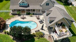 A large house with a swimming pool, multiple decks, and a well-maintained lawn. - Beautiful Kent Island Getaway with Pool (Stevensville)