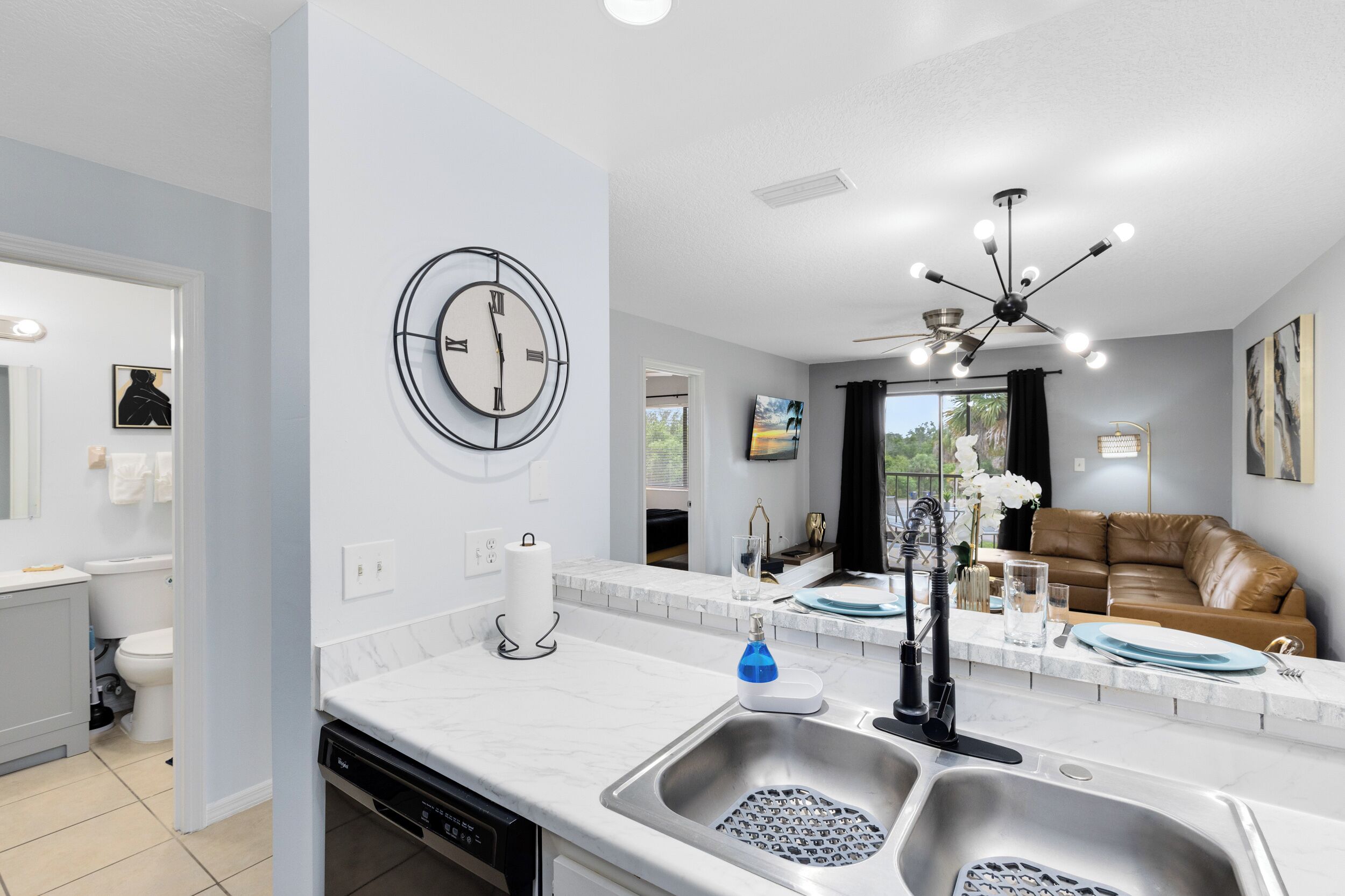 A modern kitchen with a built-in dishwasher, a sink with a faucet, and a ceiling light fixture.