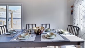 Une table à manger dressée avec des bols, des verres et des couverts, offrant une vue sur l’extérieur.