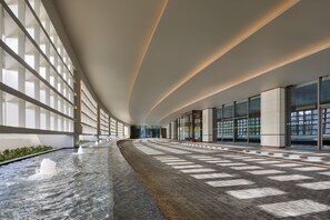 A spacious indoor corridor with a water feature, large windows, and modern architecture. - Radisson Blu Hotel, Shanghai Stadium (Shanghai)