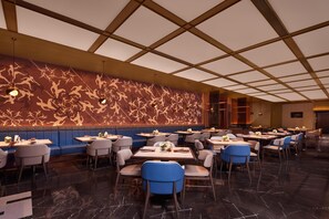 A modern restaurant with a patterned wall, blue seating, and a polished floor. - Radisson Blu Hotel, Shanghai Stadium (Shanghai)