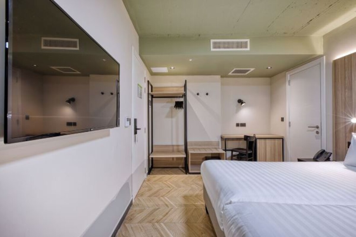 A modern hotel room with a large bed, a desk, and a walk-in closet.