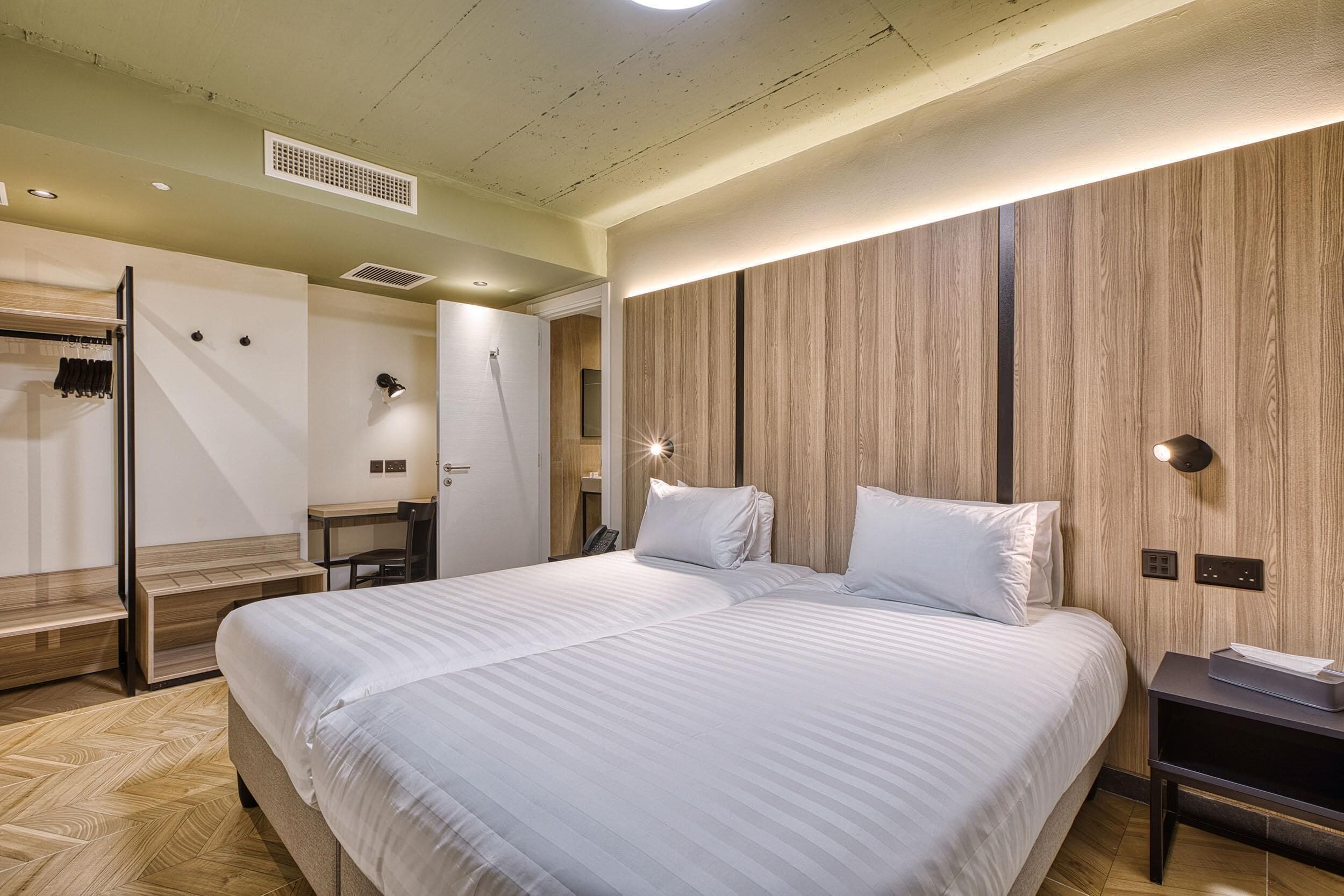 Een moderne hotelkamer met een groot bed, houten paneelwanden, een bureau en een inloopkast.