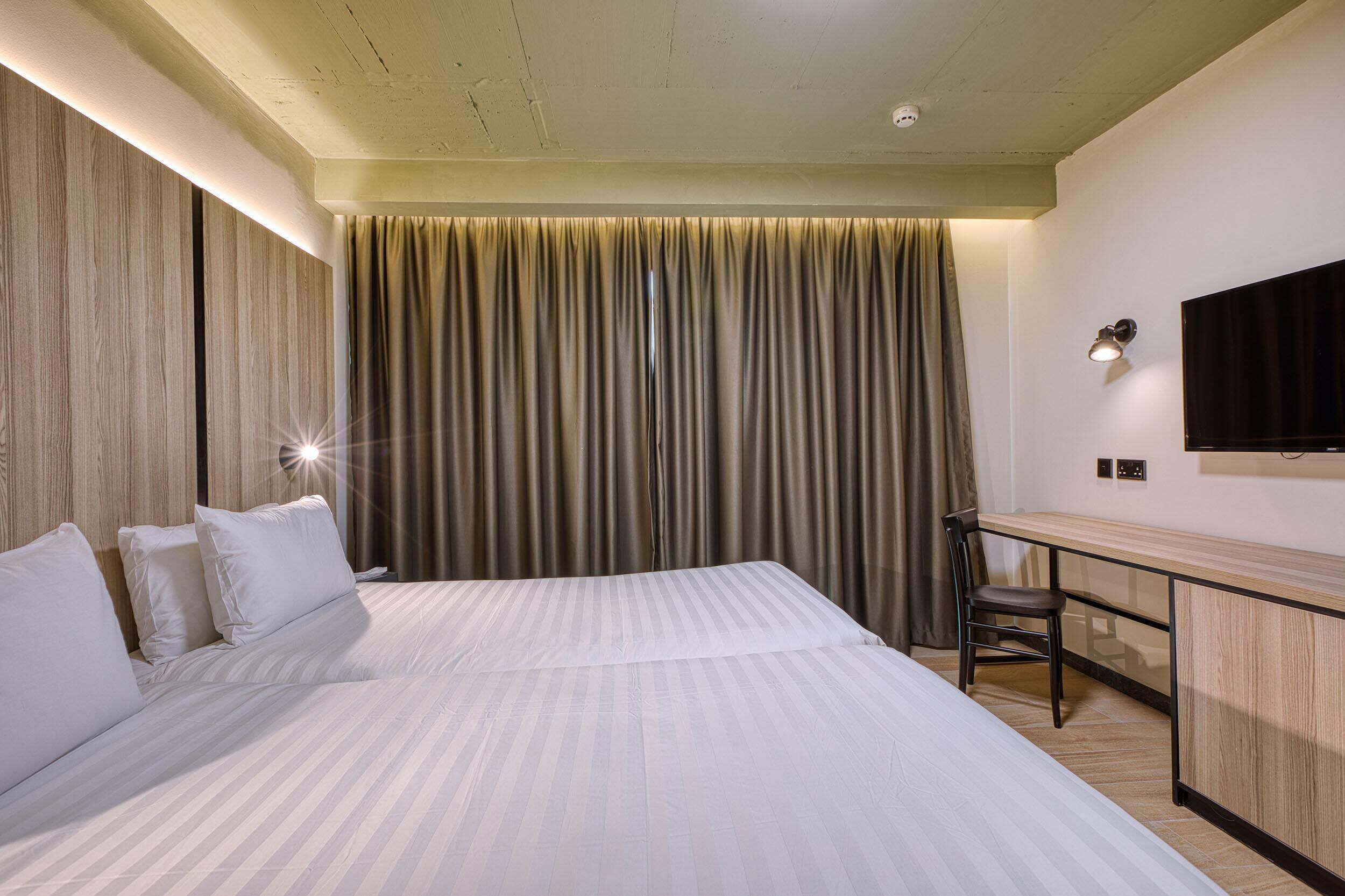 A hotel room with a large bed, a desk, and a television on the wall.