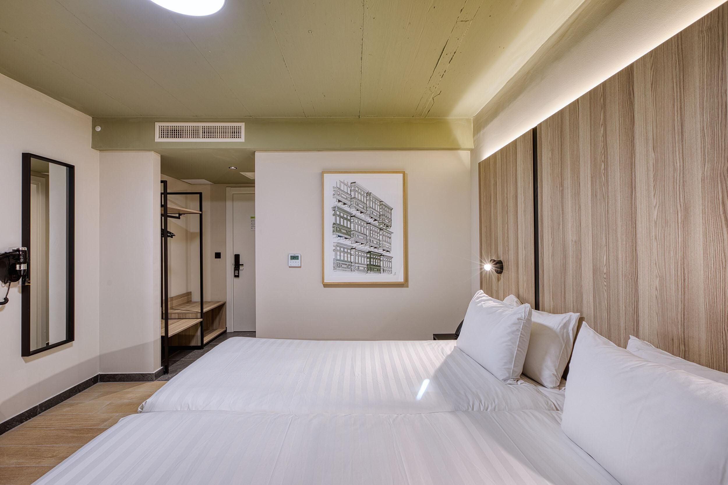 Una habitación de hotel con una cama grande, un cuadro enmarcado en la pared y un panel de madera.