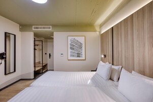 Una habitación de hotel con una cama grande, un cuadro enmarcado en la pared y un panel de madera.