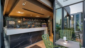A bar area with a marble counter, green chairs, and a table with a lamp. - VITA Hotel (St. Julian's)
