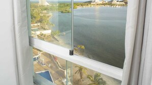 Vista desde una ventana sobre el agua, una playa y edificios.