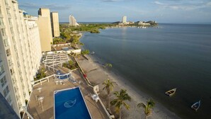 Un hotel con piscina en la azotea, vista al mar y una isla distante.