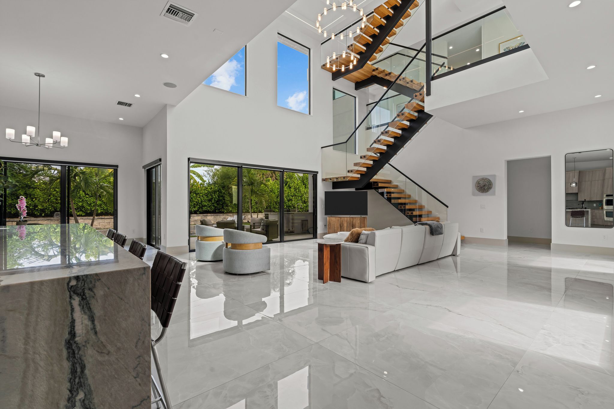 A spacious interior with a modern staircase, large windows, and a reflective floor.