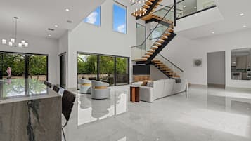 A spacious interior with a modern staircase, large windows, and a reflective floor.