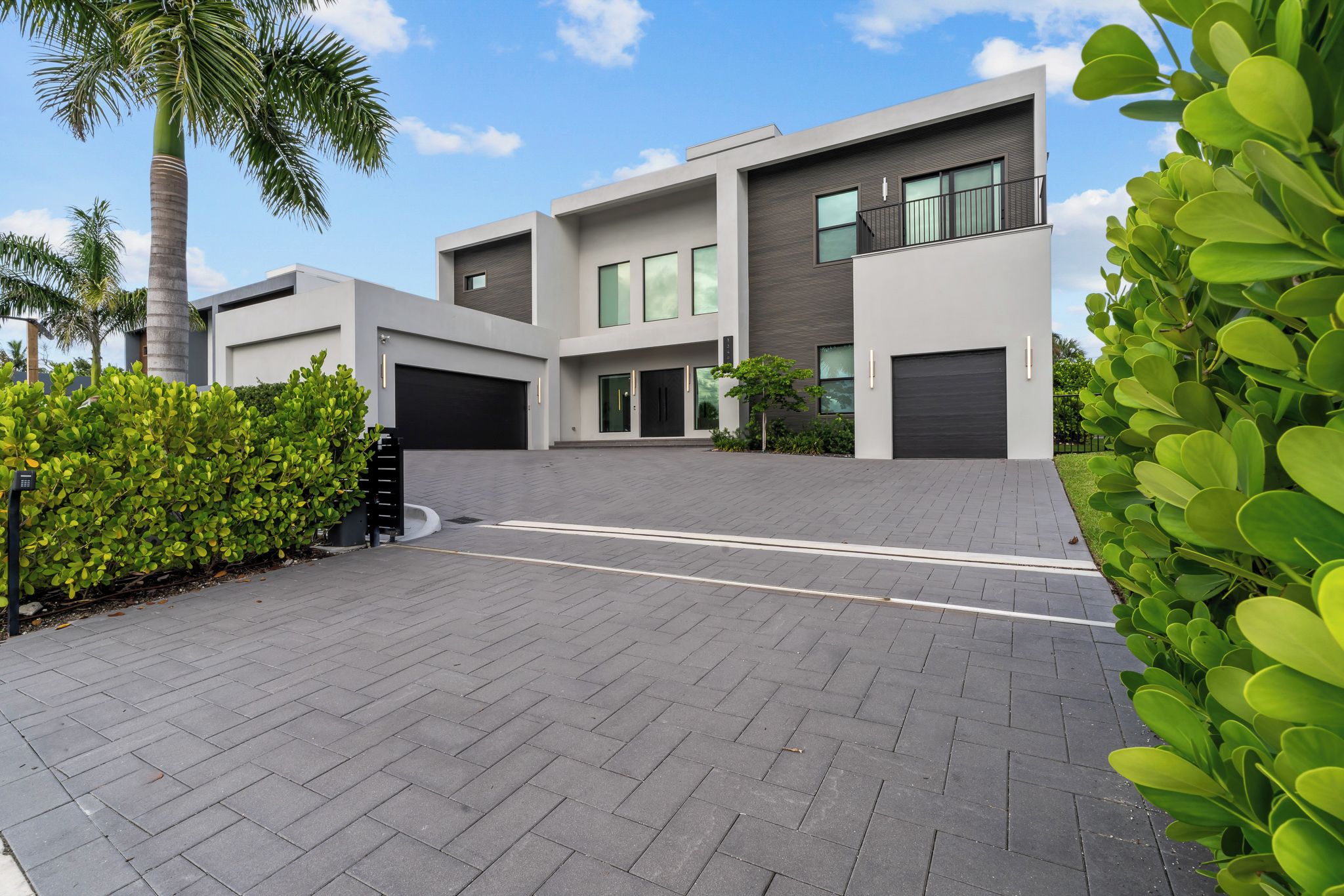 A modern two-story house with a paved driveway, large windows, and a garage.