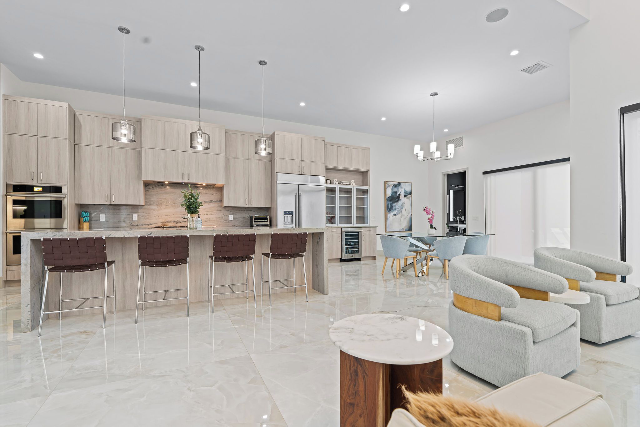 A modern kitchen with a central island, bar stools, and pendant lighting.