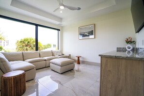 Una sala de estar moderna con un sofá seccional, una mesa de centro de madera y una cocina con encimera de mármol.