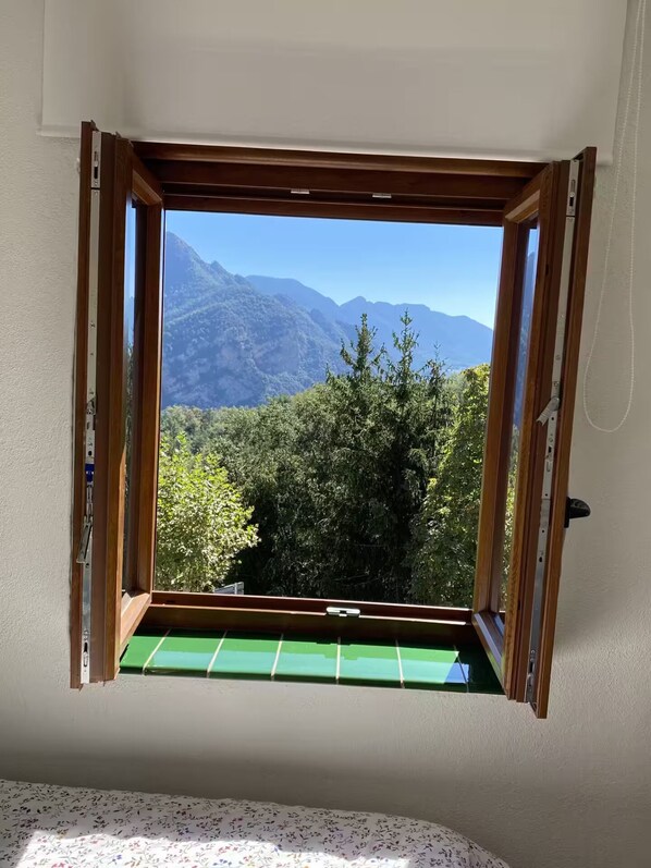 A room with a window overlooking a mountainous landscape.