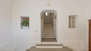 A staircase leading to a landing with a potted plant on the left and a window on the right. - Liberty Barocco - Camera Matrimoniale (Lecce)