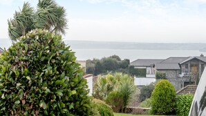Zona residencial con vista al mar, rodeada de vegetación y edificios de piedra.