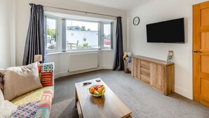 Una sala de estar moderna con sofá, mesa de centro y televisor.