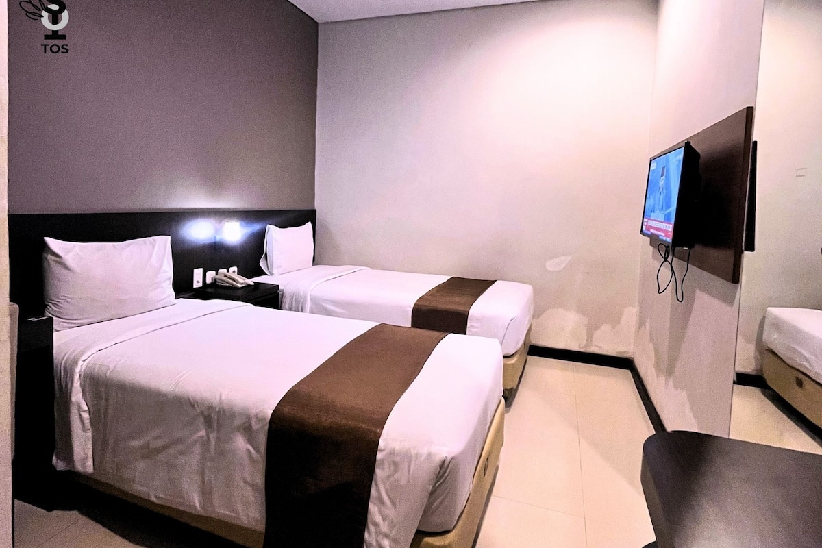 A hotel room with two beds, a TV, and a desk.