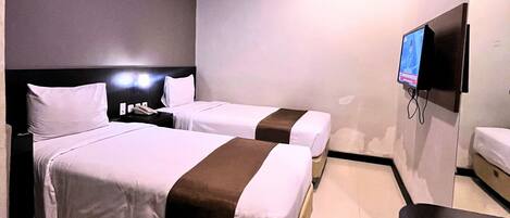 A hotel room with two beds, a TV, and a desk.