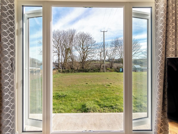 A room with a large sliding glass door leading to a grassy outdoor area with trees and a power line.