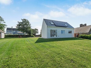 Een gelijkvloers huis met een schuin dak, zonnepanelen en een verzorgd gazon.