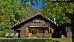 Une cabane en bois dotée d’un balcon, d’une véranda et offrant une vue sur la forêt environnante.