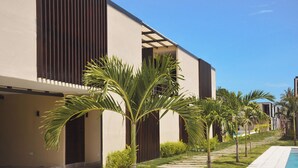 Un bâtiment moderne doté d’une piscine, de palmiers et surplombant un ciel dégagé.