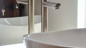 Un baño con un lavabo blanco grande, un espejo y una toalla colgada en la pared.